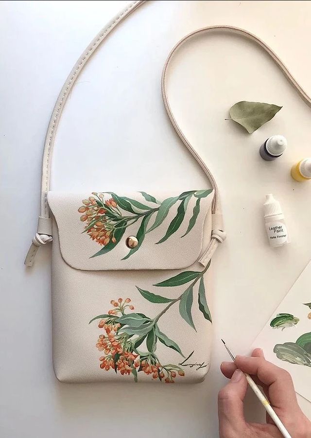 a person is painting flowers on a white bag