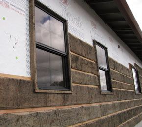 the side of a building that is under construction with windows and sidings on it