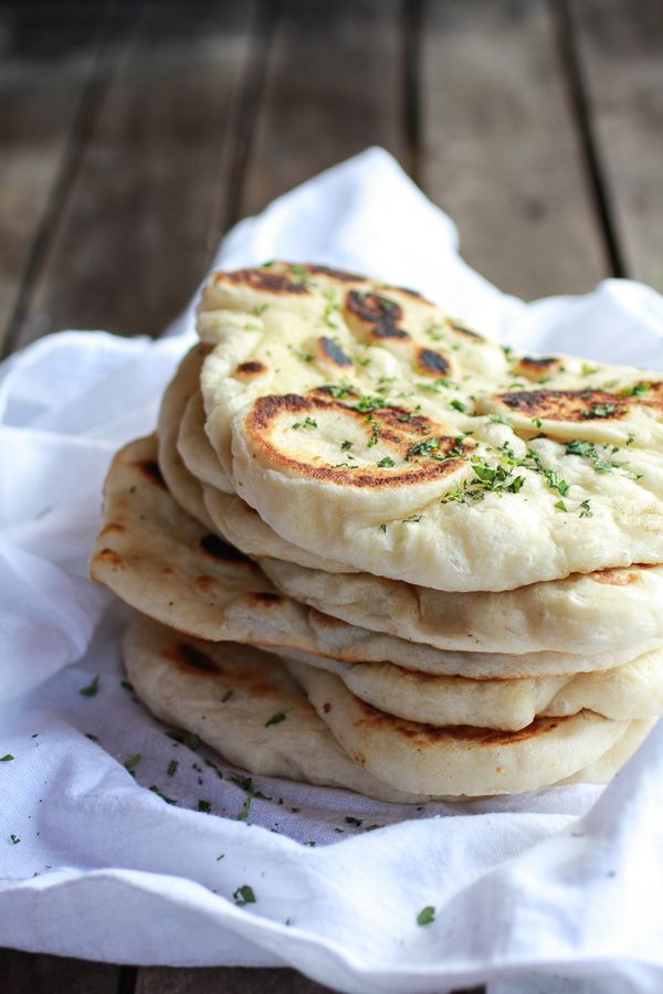 a stack of pita bread sitting on top of a white napkin next to a wooden table