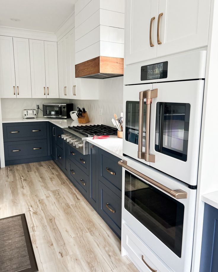 a white and blue kitchen with wood flooring on the counter tops, ovens and cabinets