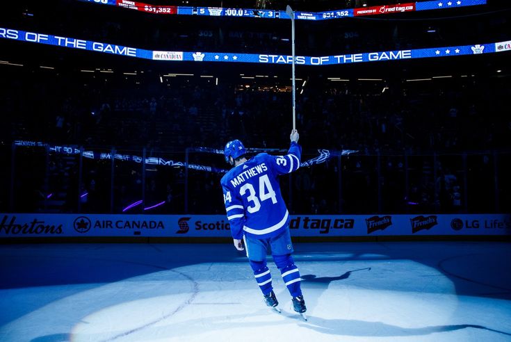 the hockey player is celebrating his goal in front of an empty arena with people watching