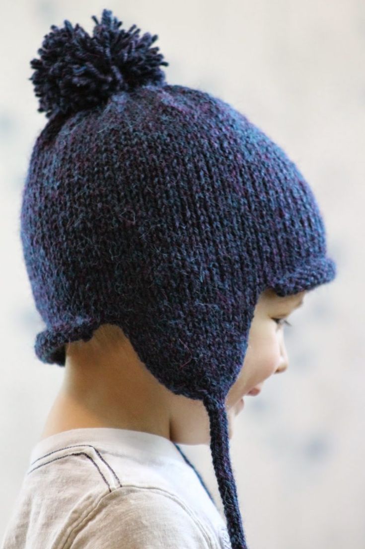 a young boy wearing a blue knitted hat with a pom - pom