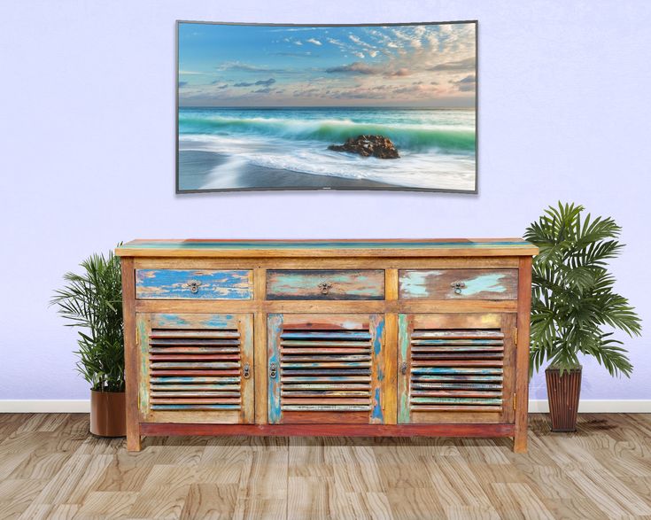 a painting hanging on the wall above a wooden cabinet with shutters in front of it