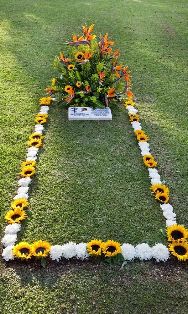 an arrangement of sunflowers and other flowers in the shape of a triangle on grass