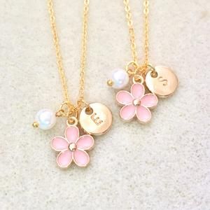 two necklaces with flowers and charms on them