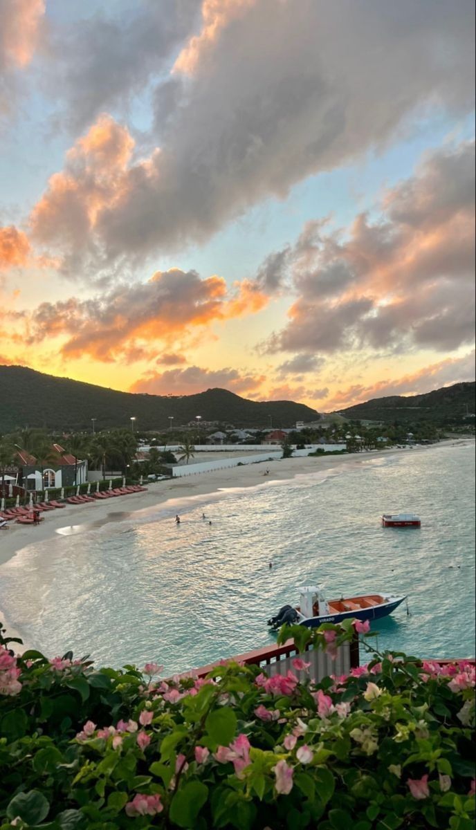 the sun is setting over an ocean with boats and buildings in the distance on the water