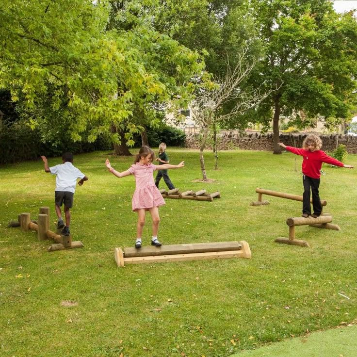 children playing on wooden obstacles in the park with their arms spread out and hands outstretched