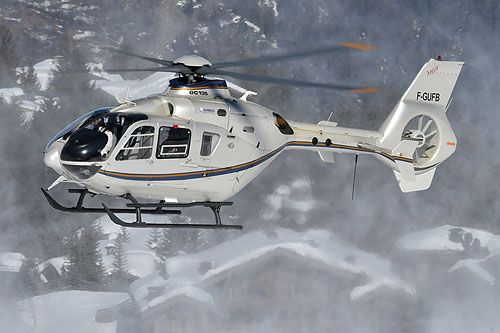 a white helicopter flying over snow covered mountains