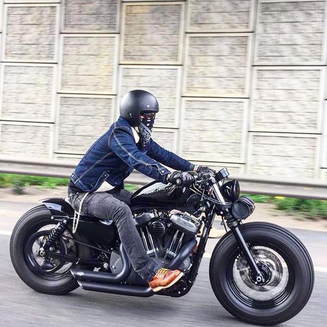 a man riding on the back of a motorcycle down a street