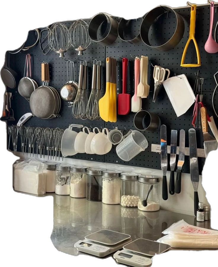 a wall mounted kitchen utensils and pans on a black pegboard with white background