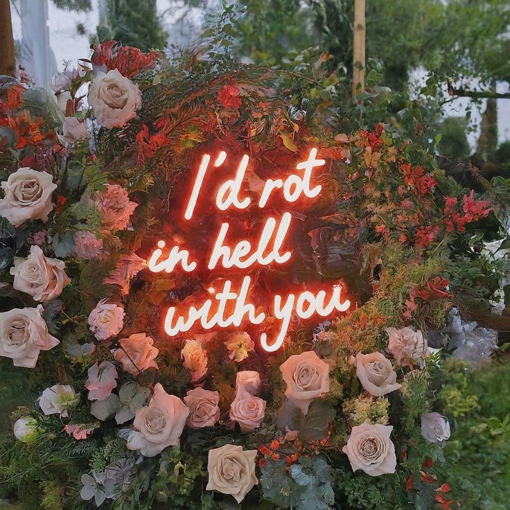 a neon sign that says i'd not in hell with you surrounded by flowers