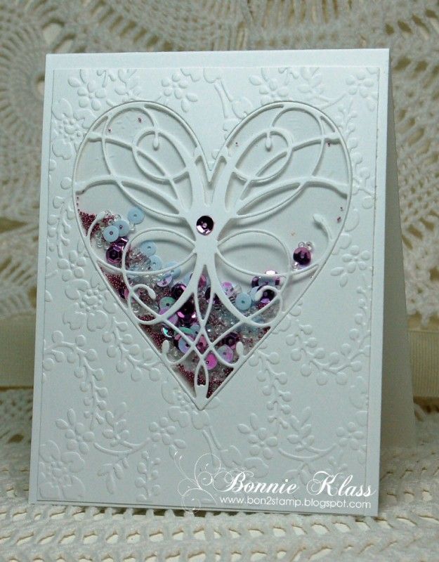 a white card with a heart shaped cutout on the front, and some beads in the middle