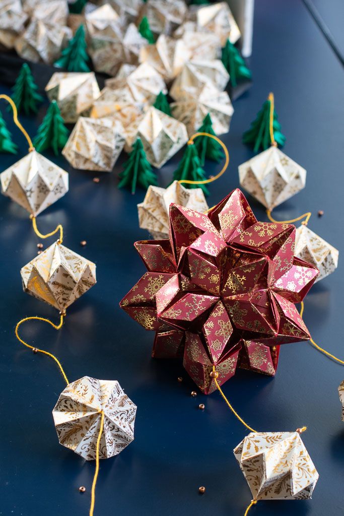 origami stars and christmas trees are on the table next to some paper balls