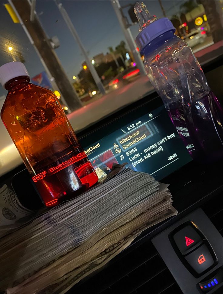 a car dashboard with two bottles on top of it next to a stack of papers