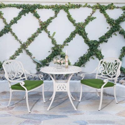 two white chairs and a table with green cushions