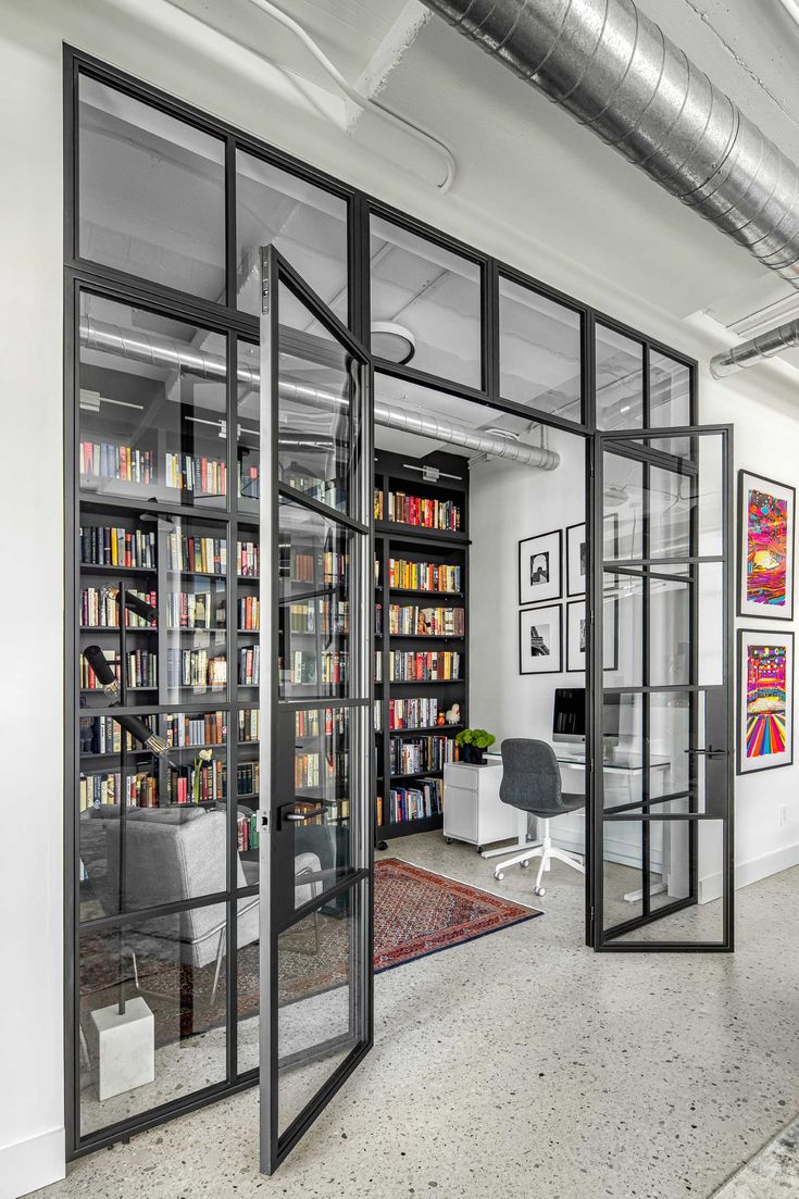 an office with lots of bookshelves and glass doors that open up to the room