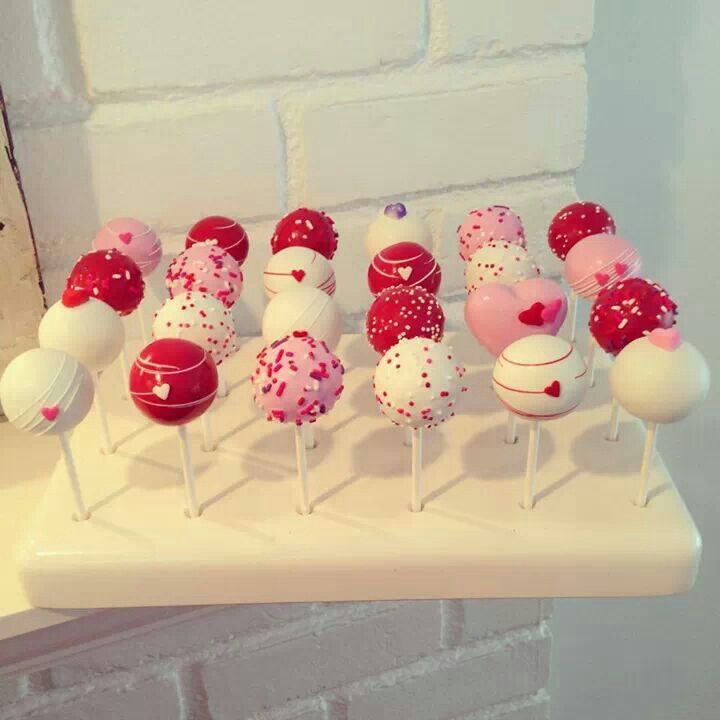 there are many cake pops with hearts on them and the words love makes the world go round