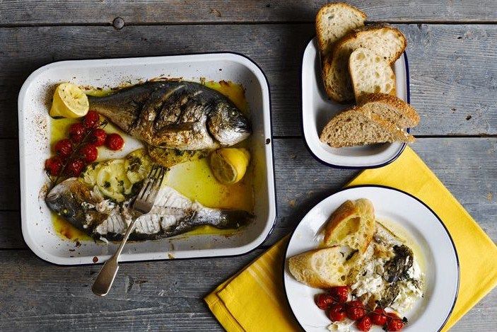 there are two plates with fish and bread on the table