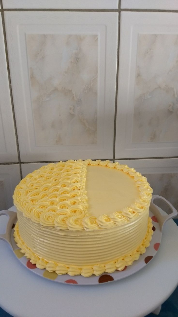 a large yellow cake sitting on top of a white plate next to a tiled wall