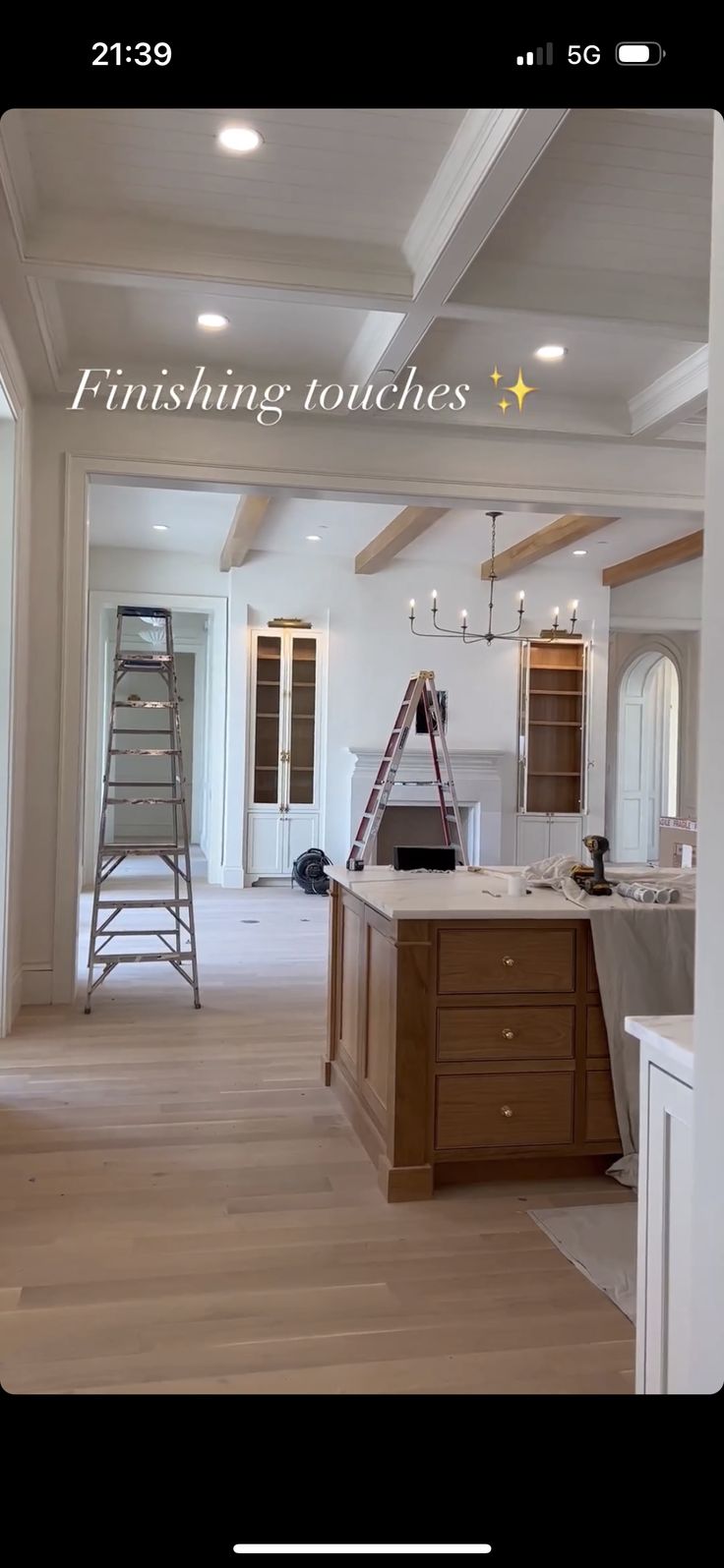 an unfinished kitchen with white walls and wood floors, including ladders to the ceiling