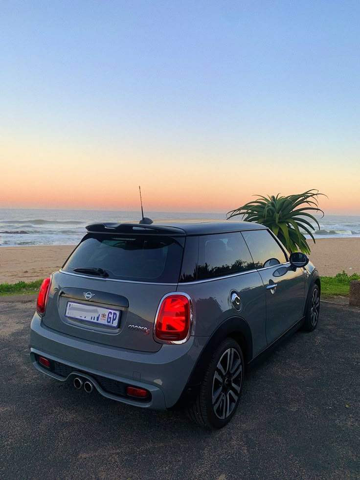 a small car is parked on the side of the road near the beach at sunset