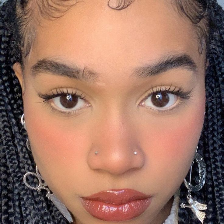 a close up of a person with braids on her head and an earring