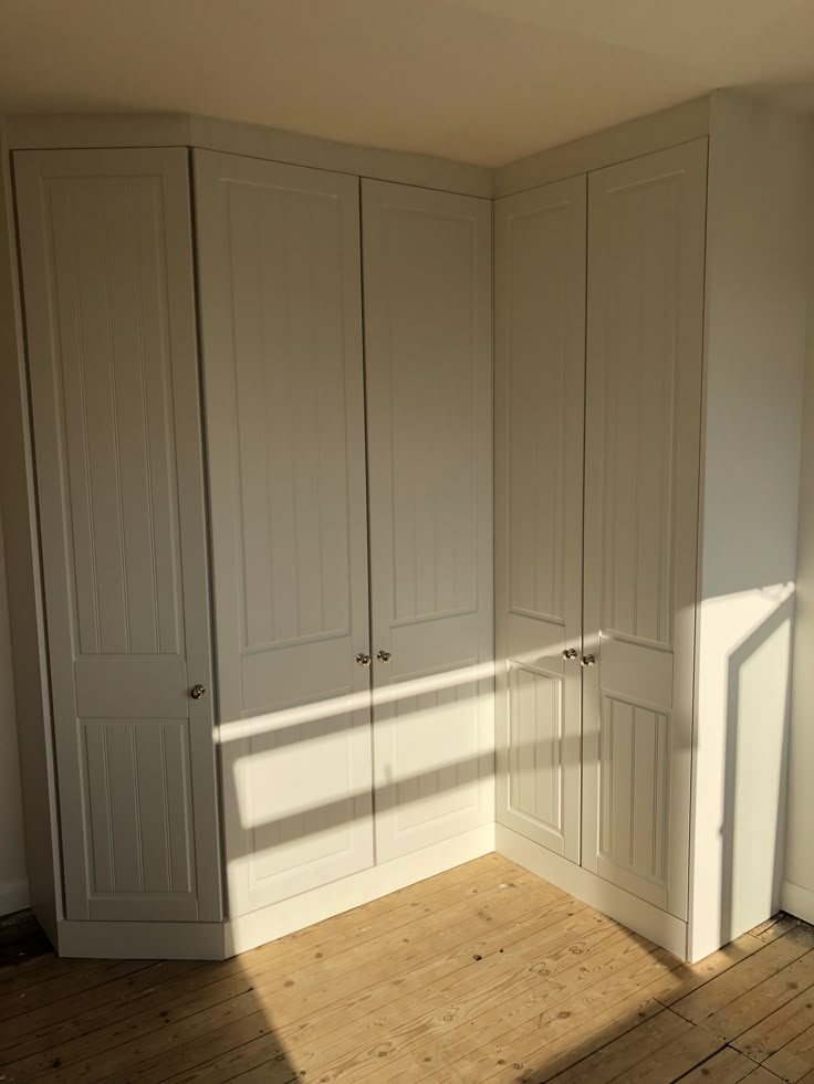 an empty room with white cupboards and wood floors