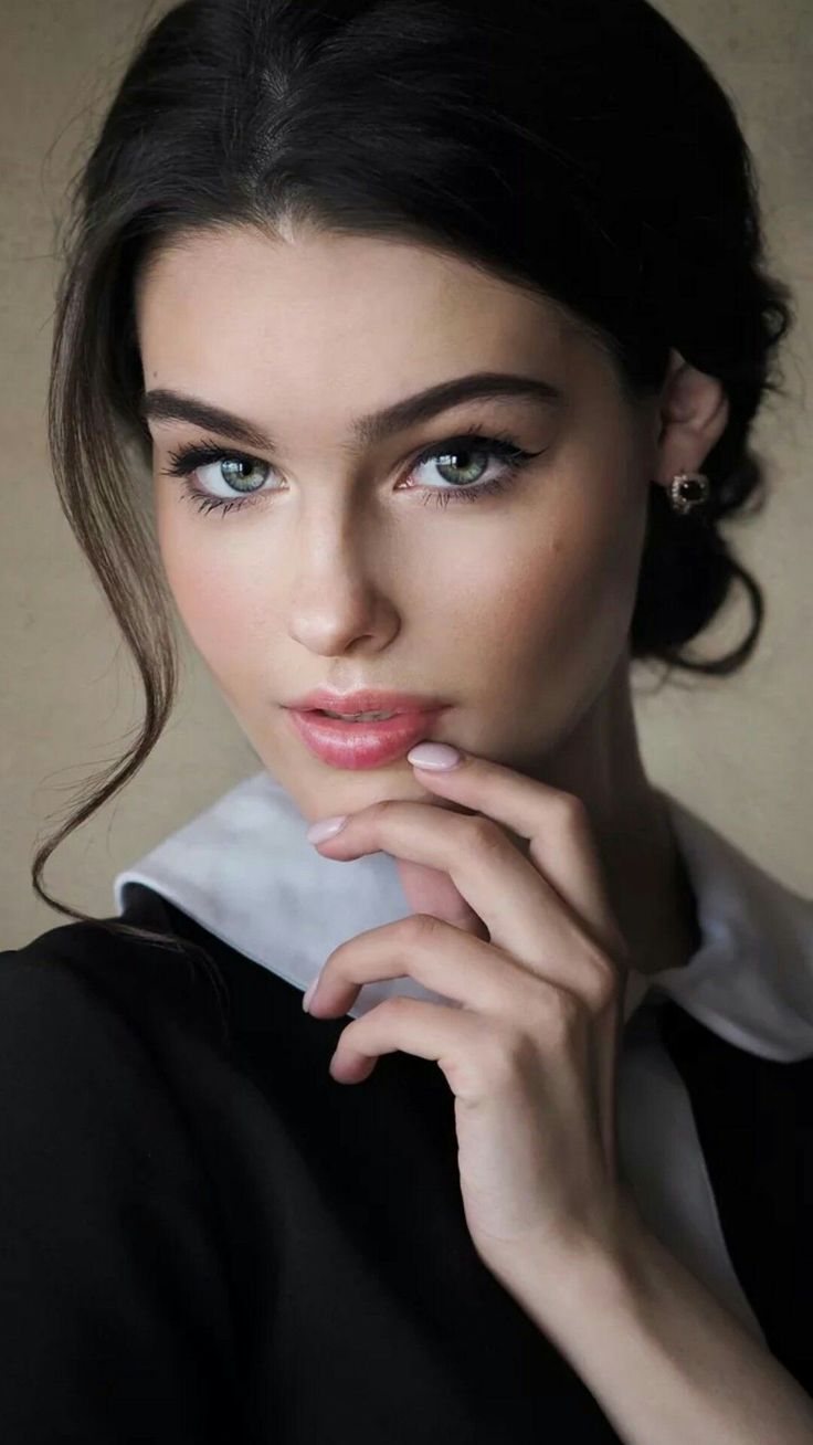 a beautiful woman with blue eyes posing for the camera, wearing a black shirt and white collar