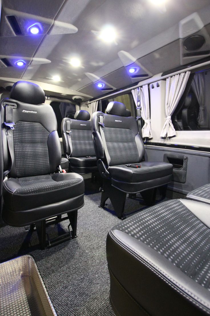 the interior of an rv with black leather seats and blue lights on the ceiling is shown