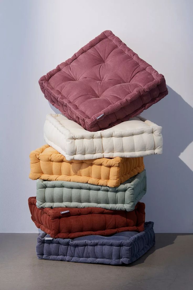 a stack of pillows sitting on top of each other in front of a white wall