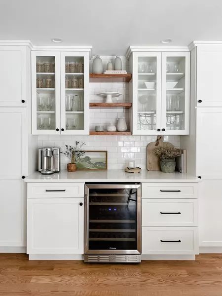 a kitchen with white cabinets and an oven in the center is filled with silverware