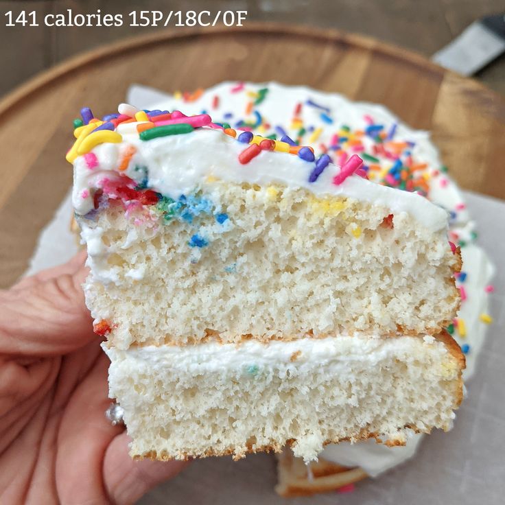 a piece of cake with white frosting and sprinkles on it being held by someone