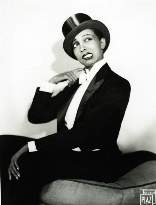 a black and white photo of a man in a top hat sitting on a chair