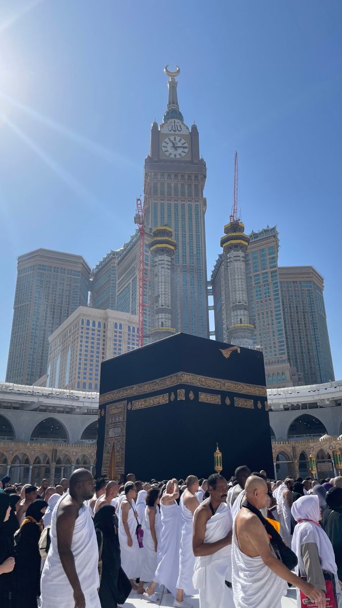 many people are gathered around the kabab in front of some tall buildings with a clock on it