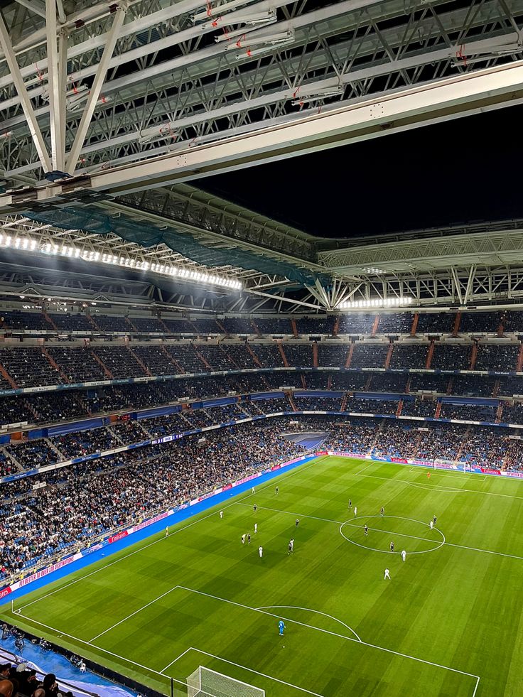 an empty soccer stadium filled with lots of people watching the game at night or onlookers