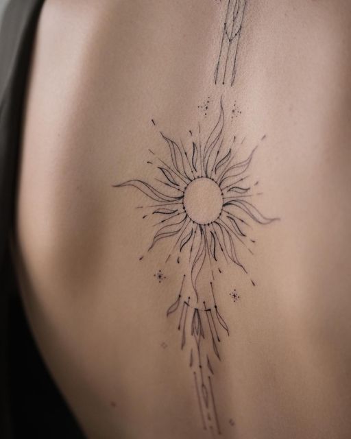 the back of a woman's stomach with a sun tattoo on her left side