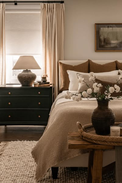 a bedroom with a bed, nightstands and flowers on the table in front of it