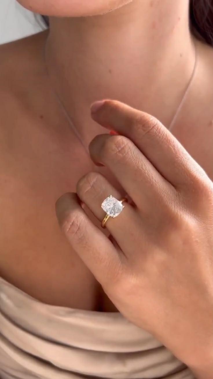 a close up of a person wearing a ring and holding her hand on her chest