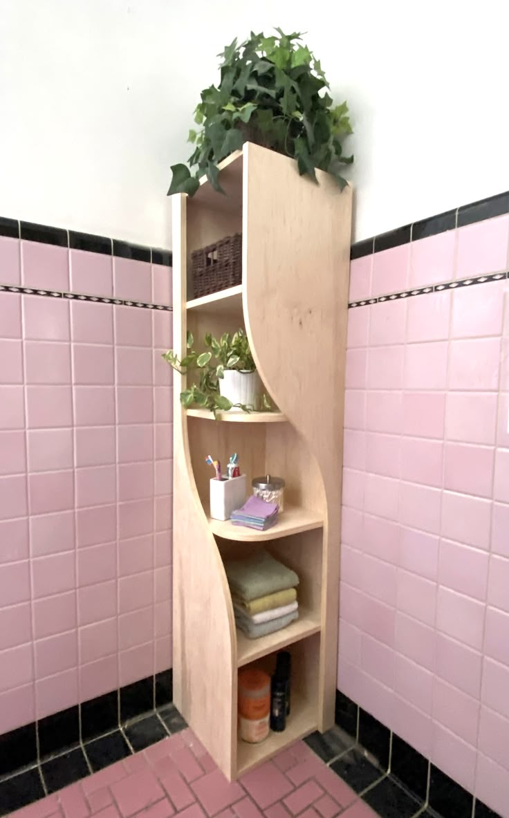 a bathroom with pink tiled walls and flooring, including a curved shelving unit