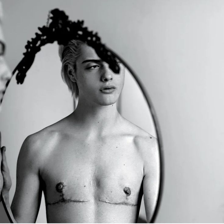 a shirtless man looking at himself in the mirror