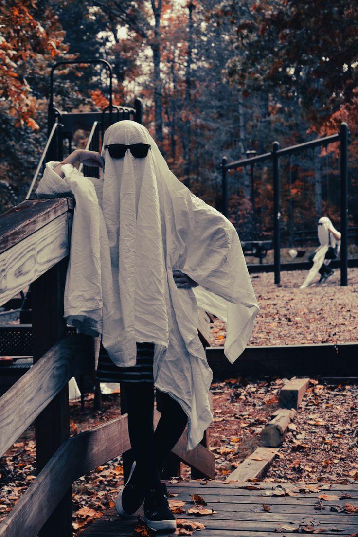 a person in a ghost costume standing on a wooden platform