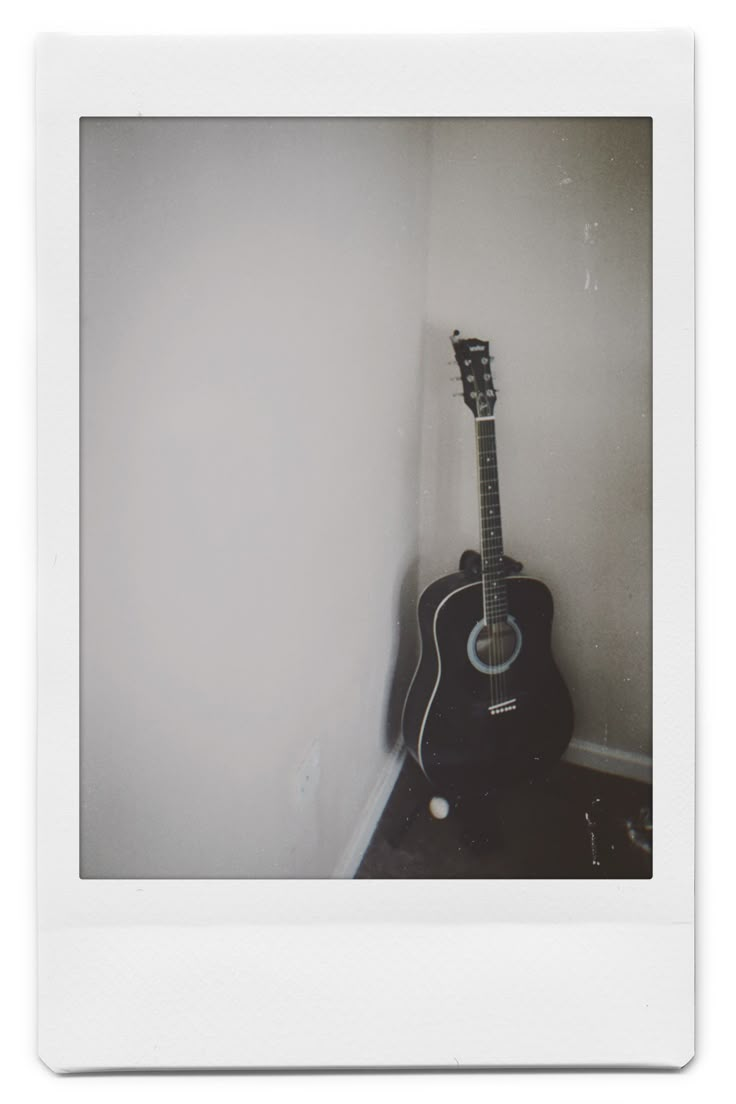 an acoustic guitar leaning against the wall