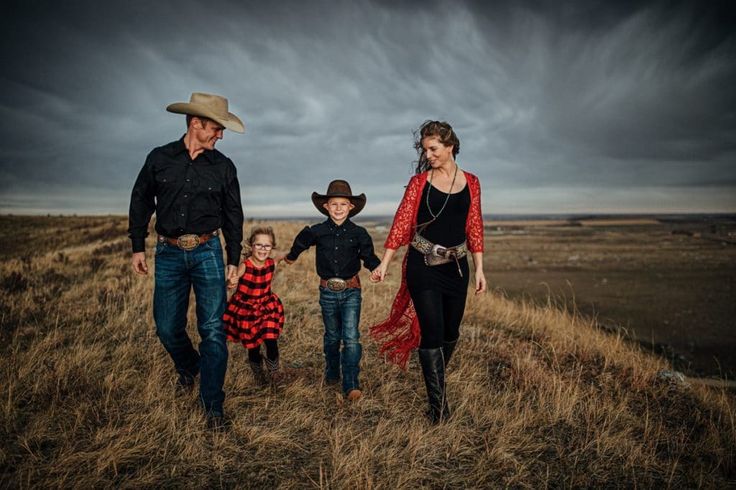 a man and two women holding hands while walking with their children on a hill side