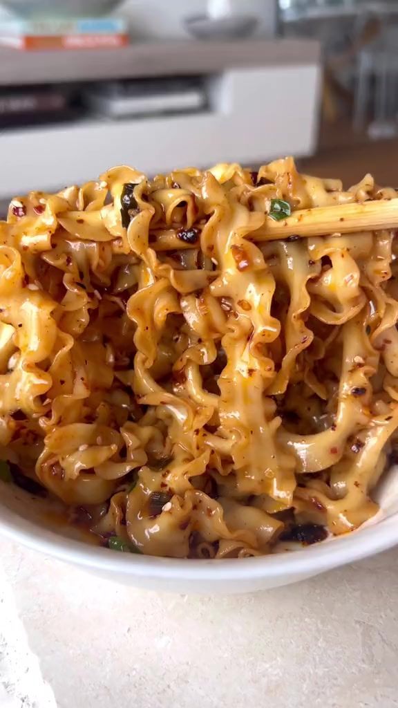 a white plate topped with noodles and chopsticks