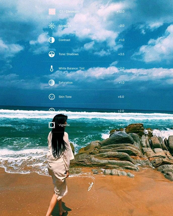 a woman standing on top of a sandy beach next to the ocean under a cloudy blue sky