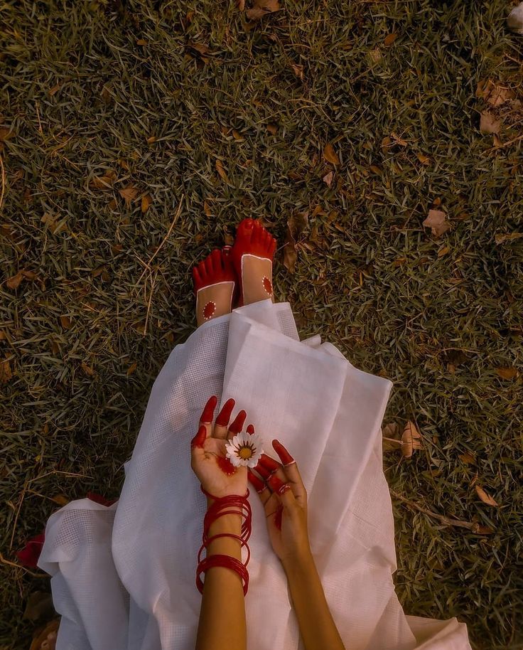 a woman in red sandals laying on top of a white cloth next to her feet