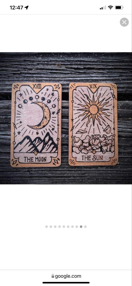 two tarot cards sitting on top of a wooden table next to an iphone screen