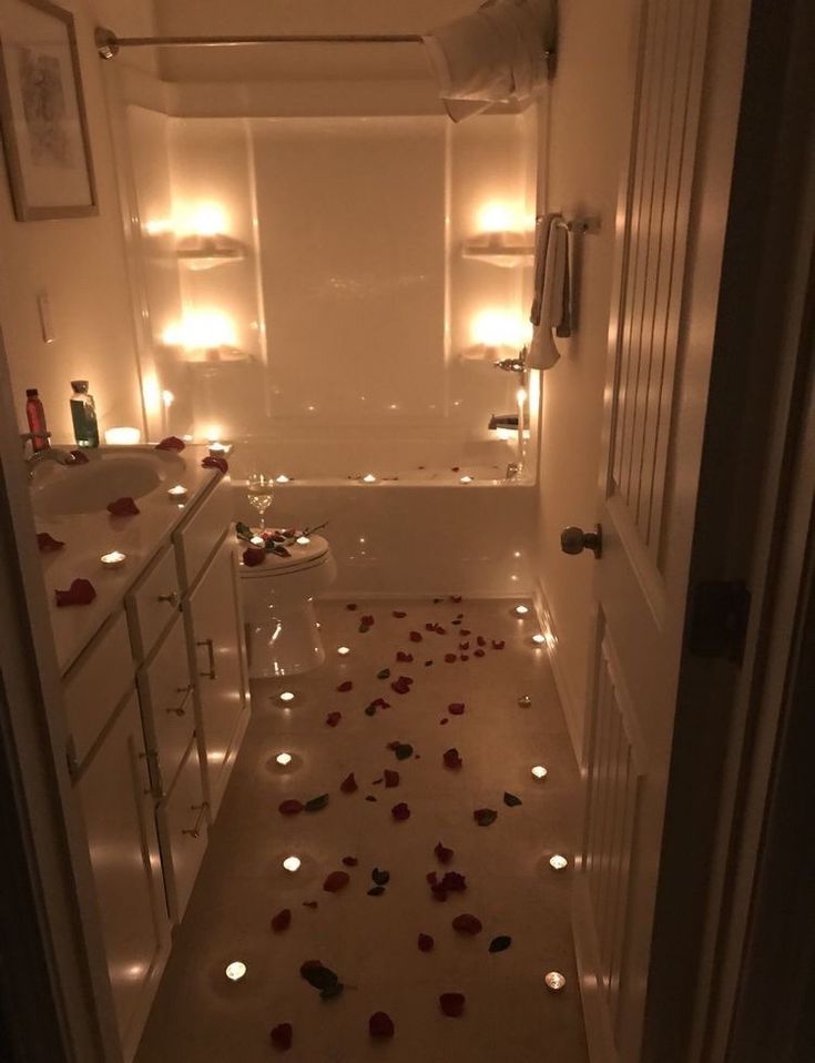 a bathroom with candles and rose petals on the floor