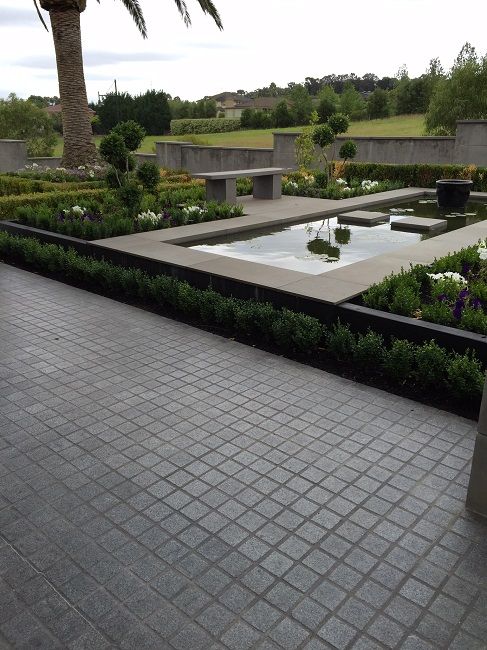 an outdoor garden with plants and water features in the center, surrounded by concrete blocks