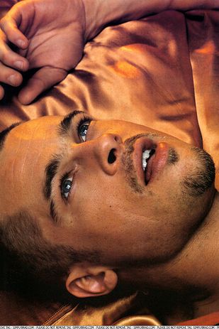 a close up of a person laying on a bed with his hand over his head